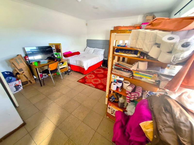 A bedroom featuring tiled flooring and coved ceilings, currently utilized as a multi-purpose living and storage space.