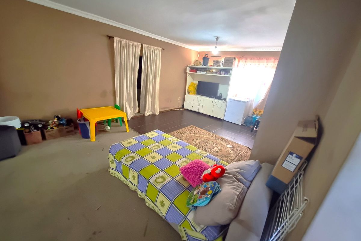 A spacious living area featuring a combination of carpeted and tiled flooring with coved ceiling details, offering a versatile layout for family living.