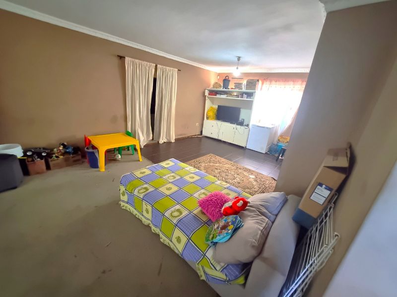 A spacious living area featuring a combination of carpeted and tiled flooring with coved ceiling details, offering a versatile layout for family living.