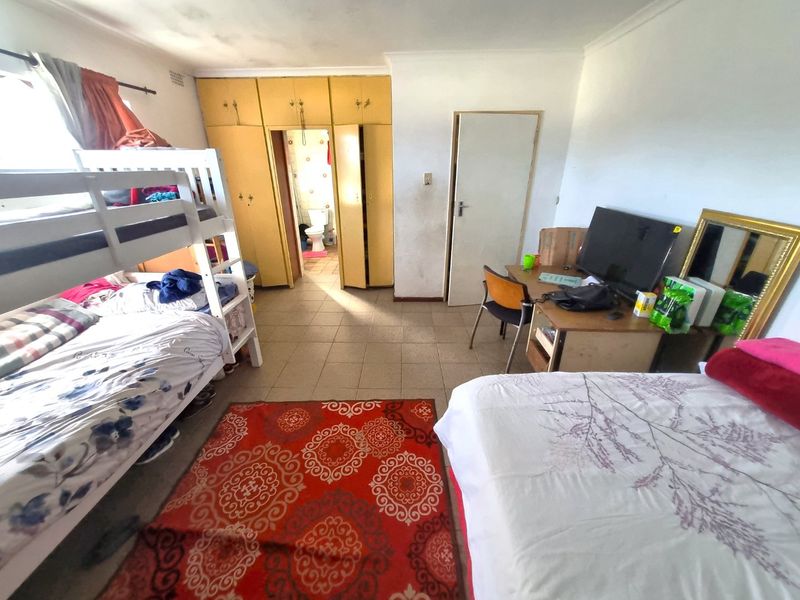 A bedroom featuring tiled flooring, built-in cupboards, and direct access to an en-suite bathroom.