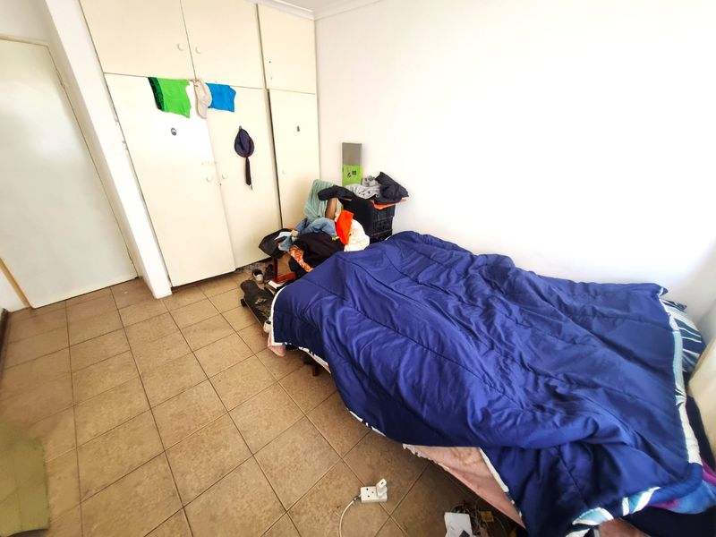 A bedroom featuring tiled flooring and built-in cupboards, providing functional storage space.