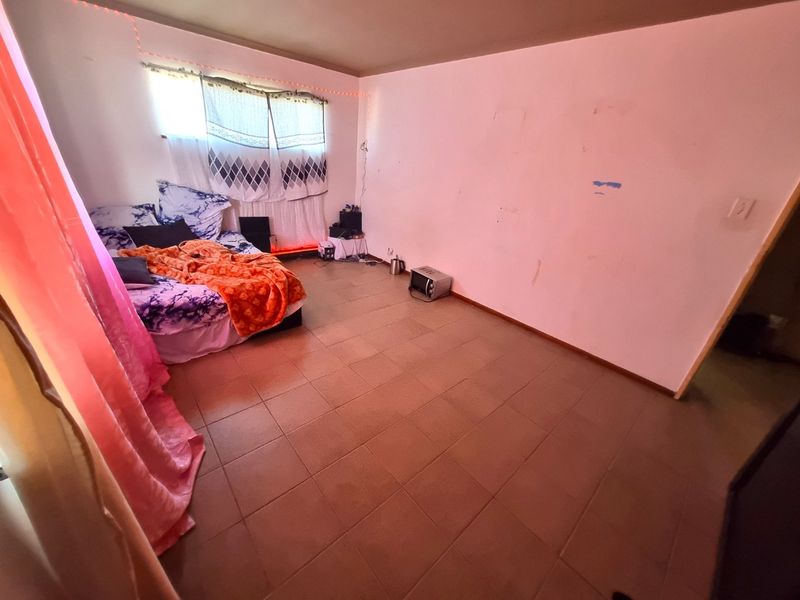 A bedroom featuring tiled flooring and plain walls, currently requiring cosmetic updates and fresh paint to improve its overall presentation.