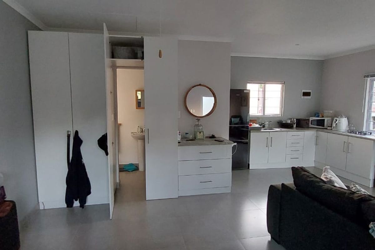 Open-plan living area featuring a functional kitchen with built-in cabinetry, tiled flooring, and direct access to an adjacent bathroom.