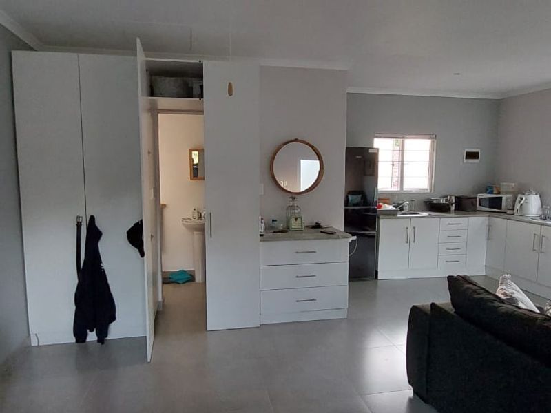 Open-plan living area featuring a functional kitchen with built-in cabinetry, tiled flooring, and direct access to an adjacent bathroom.
