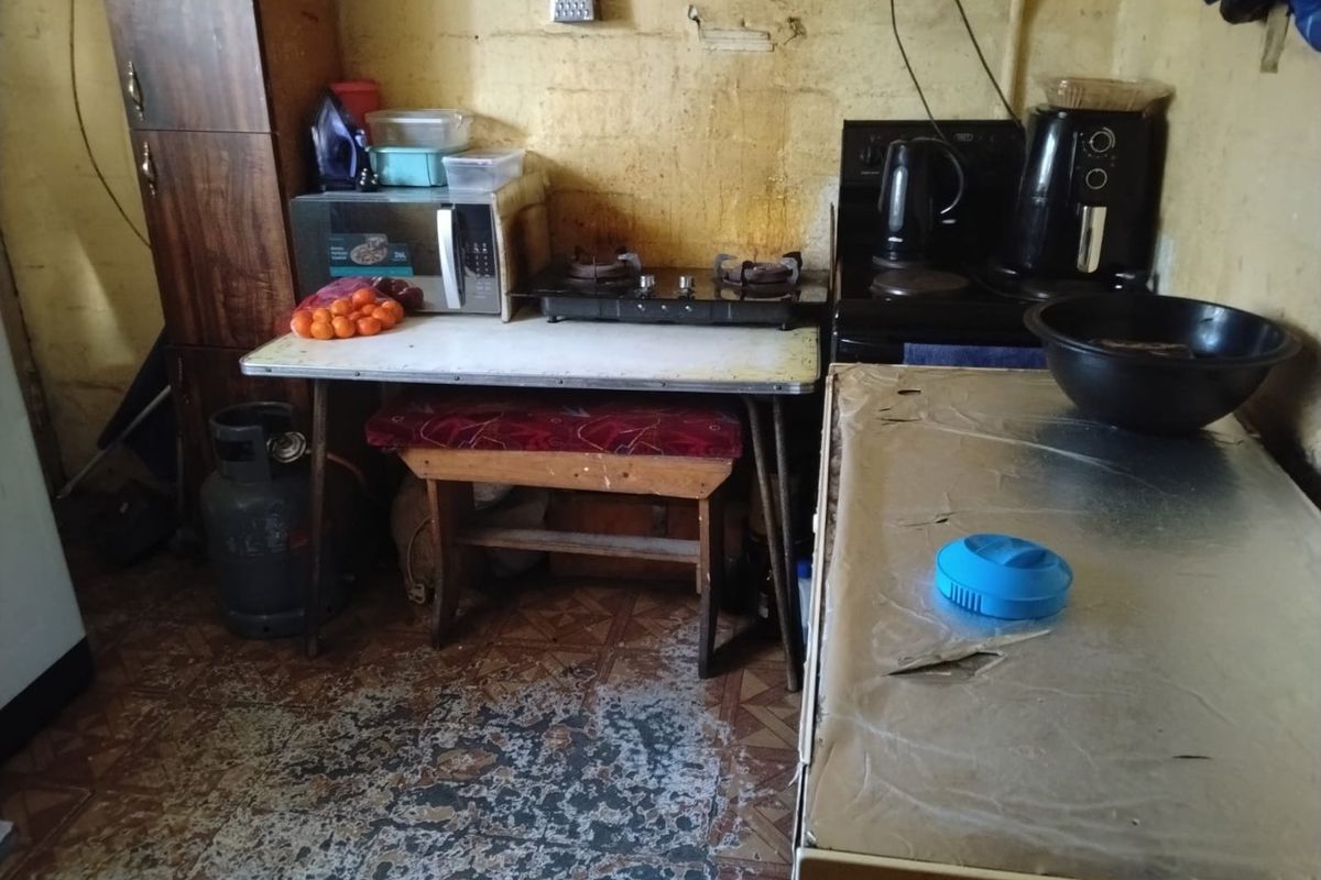 A small kitchen area featuring a gas hob and electric stove, requiring significant renovation and cosmetic updates to improve the overall condition.