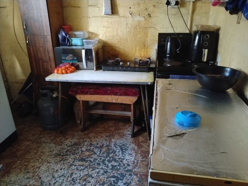 A small kitchen area featuring a gas hob and electric stove, requiring significant renovation and cosmetic updates to improve the overall condition.