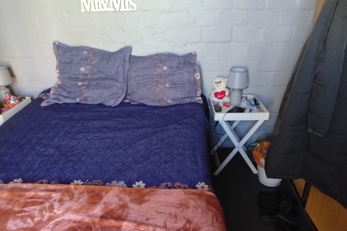 A bedroom featuring a painted brick feature wall, providing a textured backdrop for the sleeping area.