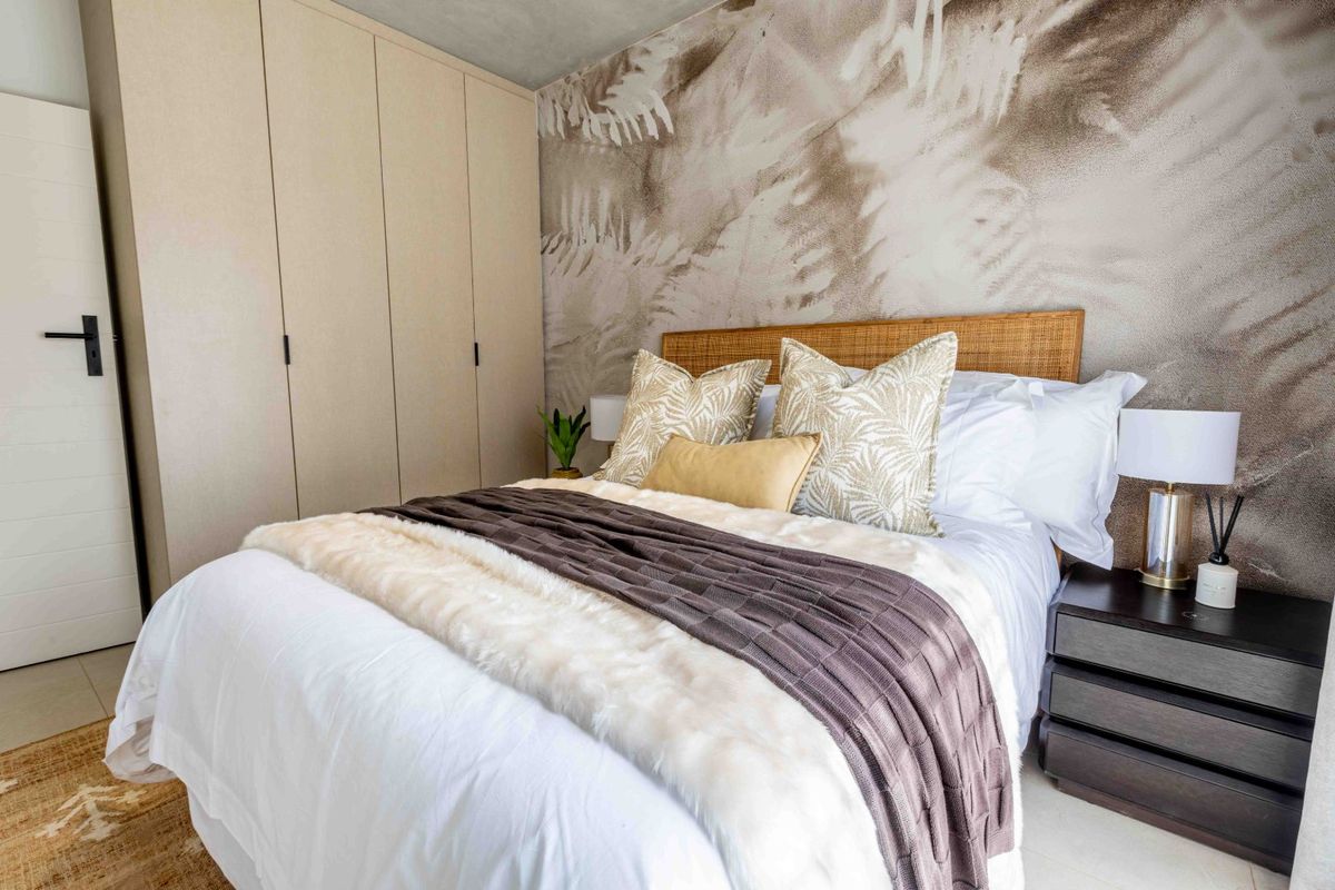 A well-appointed bedroom featuring neutral-toned built-in cupboards, a decorative feature wall, and modern tiled flooring.