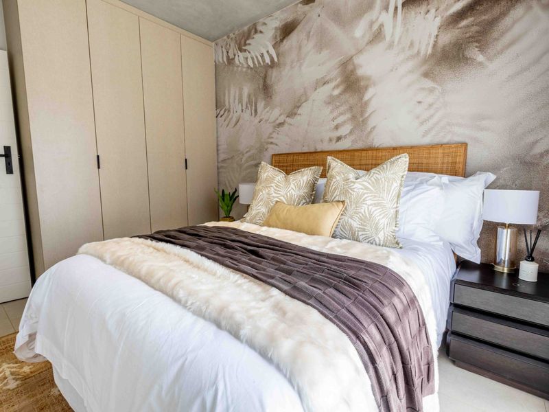 A well-appointed bedroom featuring neutral-toned built-in cupboards, a decorative feature wall, and modern tiled flooring.
