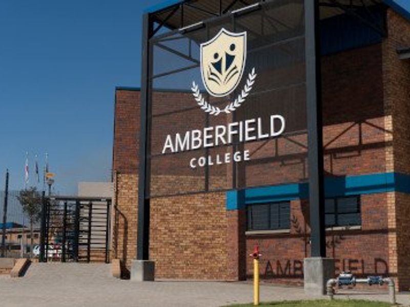 Front exterior view of Amberfield College featuring a brick facade, prominent signage, and secure gated entrance.