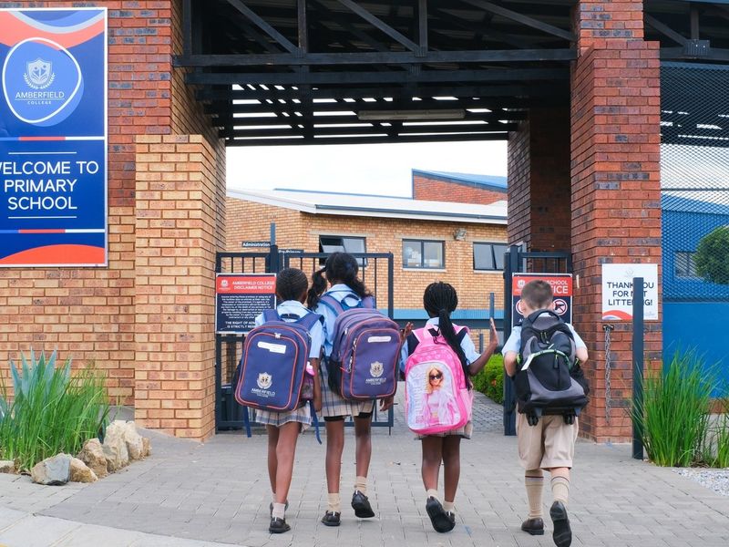The main entrance to the school facility featuring a brick facade, secure metal gate, and paved pedestrian access.