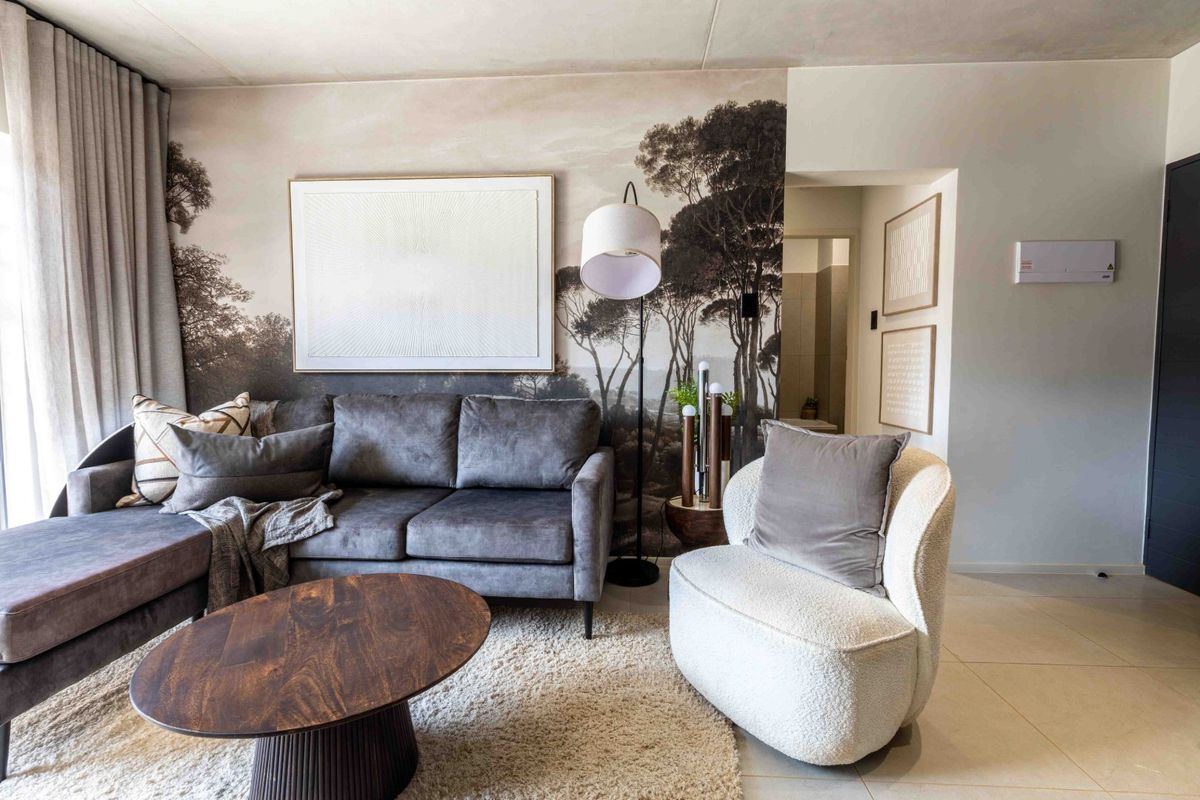 A well-maintained living room featuring neutral tiled flooring, floor-to-ceiling curtains, and a decorative feature wall, creating a comfortable and modern living space.