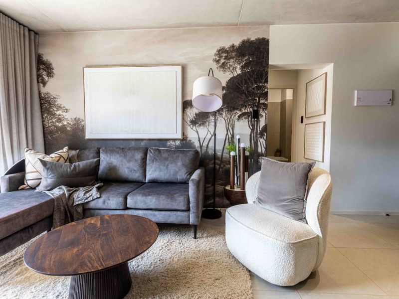 A well-maintained living room featuring neutral tiled flooring, floor-to-ceiling curtains, and a decorative feature wall, creating a comfortable and modern living space.
