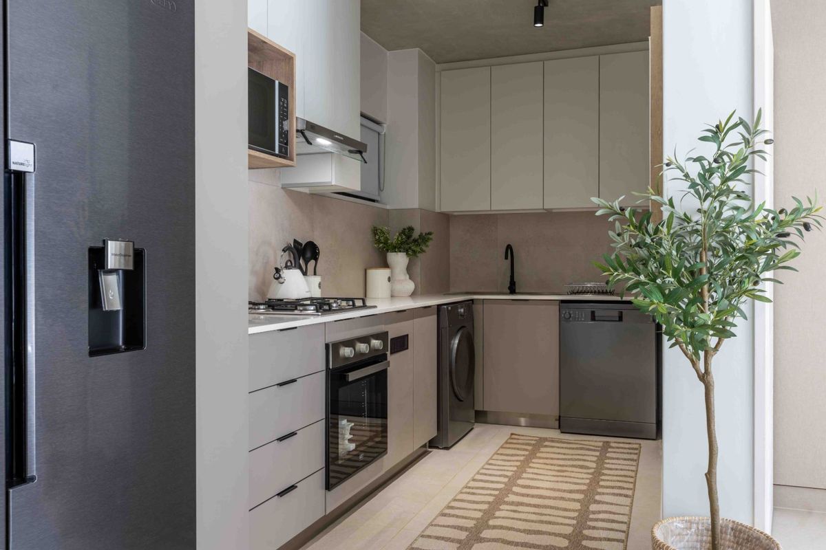 Modern, compact kitchen featuring sleek cabinetry, stone countertops, integrated appliances, and high-quality finishes in a neutral, contemporary palette.