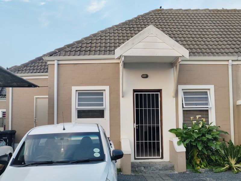 Front elevation of the house featuring a tiled roof, entrance canopy, and secure metal gate at the main doorway.