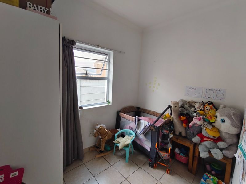 A compact bedroom featuring tiled flooring and a top-hung window, currently utilized as a nursery.