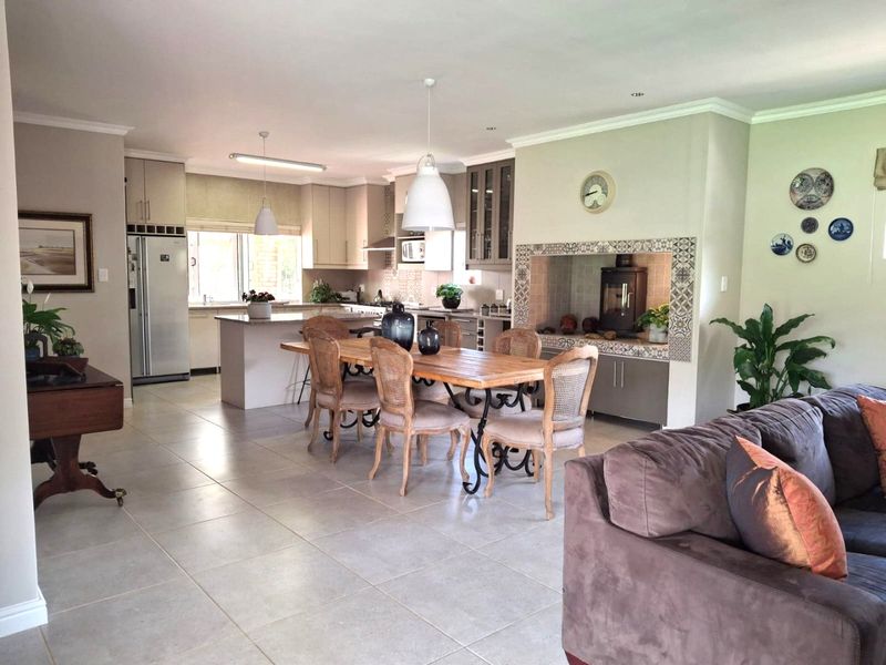 Spacious open-plan living area featuring a modern kitchen with island, dining space, and a built-in fireplace with decorative tiling.