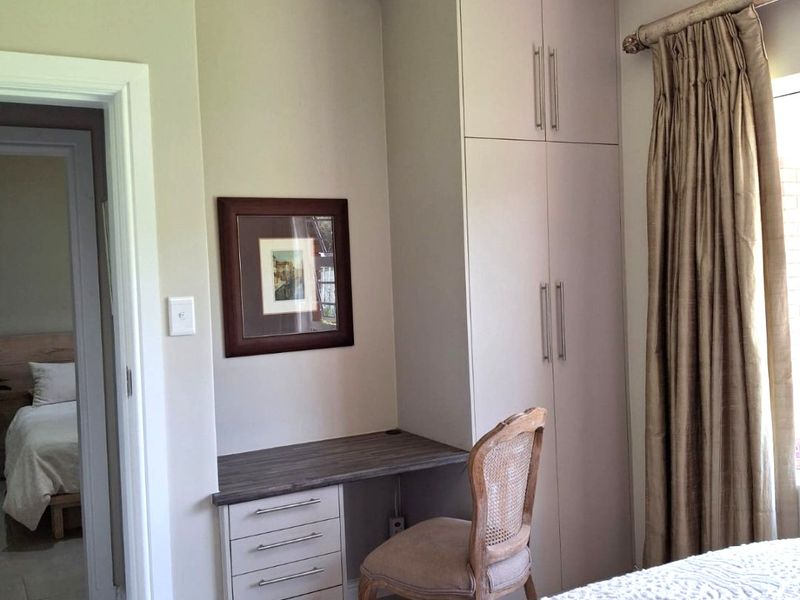 A well-maintained bedroom featuring built-in cabinetry with an integrated desk, crown molding, and neutral tiled flooring.