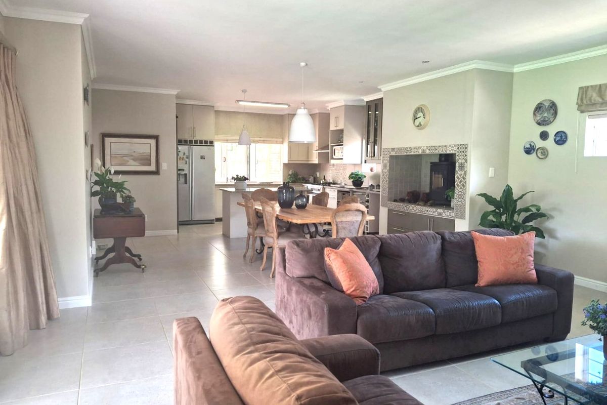 Spacious open-plan living and dining area featuring tiled floors, a modern kitchen with built-in cabinetry, and a feature fireplace.