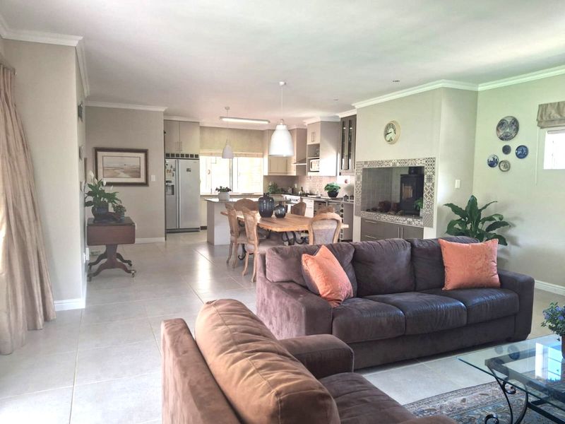 Spacious open-plan living and dining area featuring tiled floors, a modern kitchen with built-in cabinetry, and a feature fireplace.