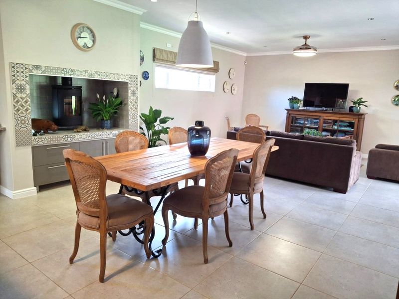 Spacious open-plan living and dining area featuring tiled flooring, a built-in fireplace with decorative tiling, and recessed ceiling lighting.
