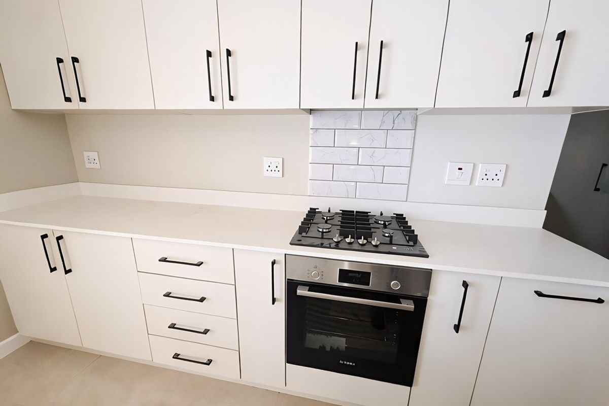 Modern kitchen featuring white cabinetry, stone countertops, a gas hob, and a built-in oven with a marble-look subway tile splashback.