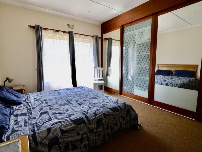 A bedroom featuring a large built-in wardrobe with sliding mirror doors and carpeted flooring.