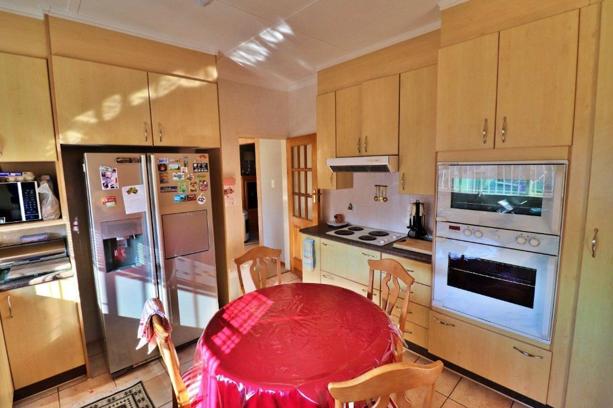 A functional kitchen featuring light wood-toned cabinetry, built-in oven, extractor fan, and tiled flooring, offering a practical layout for daily meal preparation.