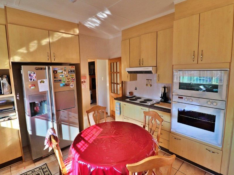 A functional kitchen featuring light wood-toned cabinetry, built-in oven, extractor fan, and tiled flooring, offering a practical layout for daily meal preparation.