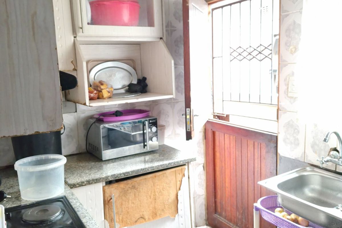 Compact kitchen featuring granite countertops, built-in cabinetry, and an electric hob, with direct access to the exterior via a security-gated door.