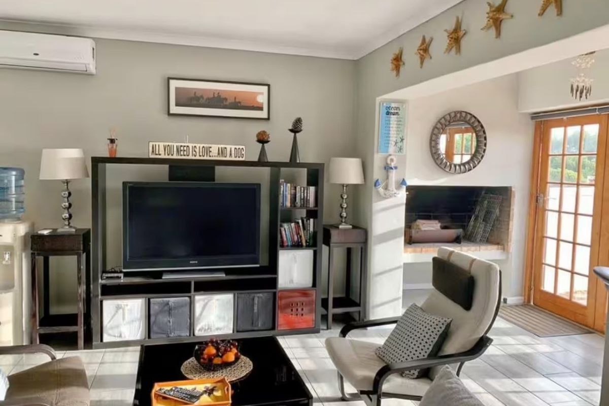 A comfortable living room featuring tiled flooring, a built-in fireplace, and a split-system air conditioner, with direct access to the outdoor area.