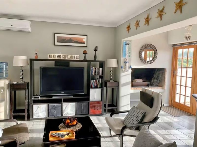 A comfortable living room featuring tiled flooring, a built-in fireplace, and a split-system air conditioner, with direct access to the outdoor area.