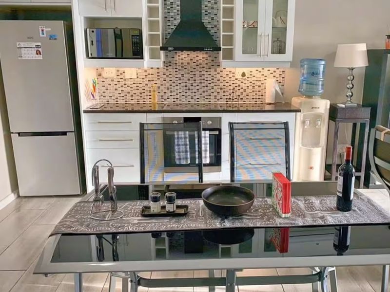 A functional kitchen featuring white cabinetry, a mosaic tile backsplash, built-in oven, extractor fan, and integrated microwave, complemented by tiled flooring.