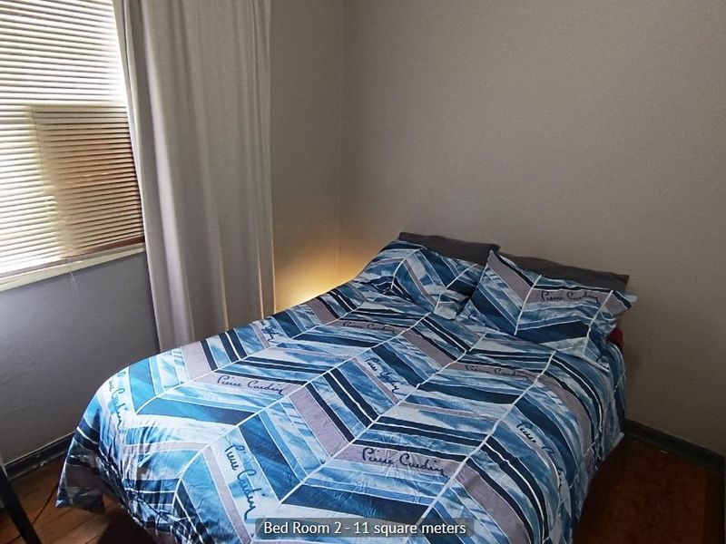 A compact bedroom featuring neutral wall finishes and window treatments, providing a functional space for rest.