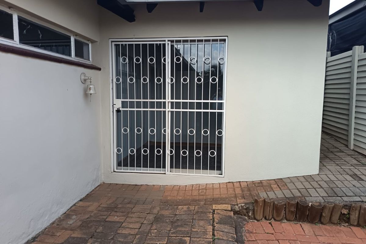 Rear exterior view featuring a paved patio area with a sliding door protected by a white security gate.
