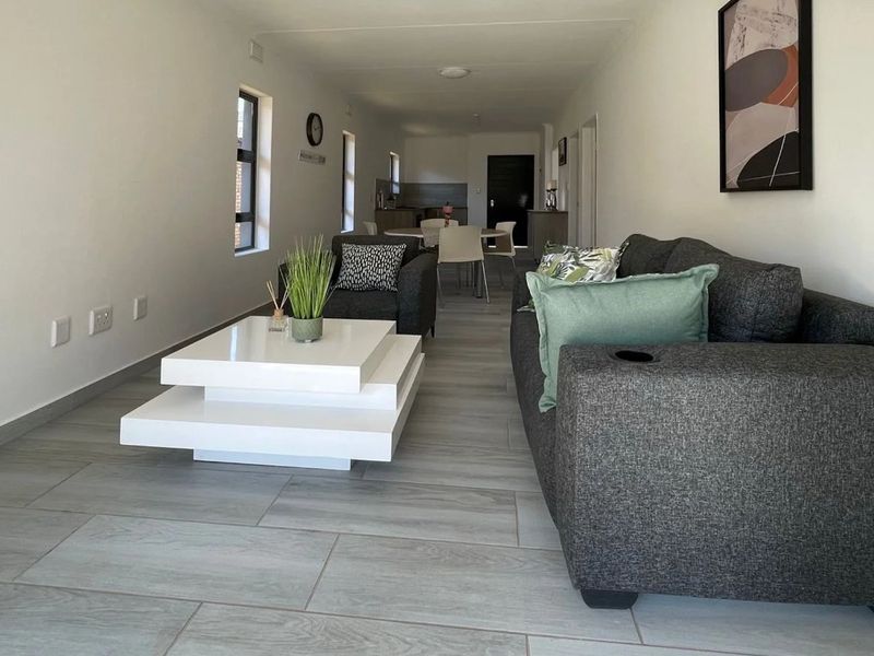An open-plan living and dining area featuring modern tiled flooring and neutral wall finishes, providing a bright and functional space.