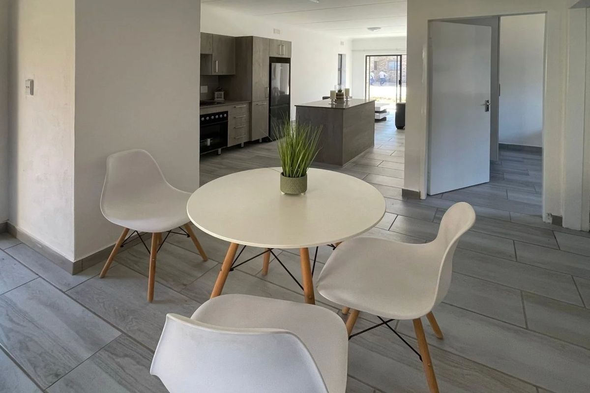 Open plan living area featuring modern tiled flooring, a contemporary kitchen with island, and seamless flow between the dining and kitchen spaces.