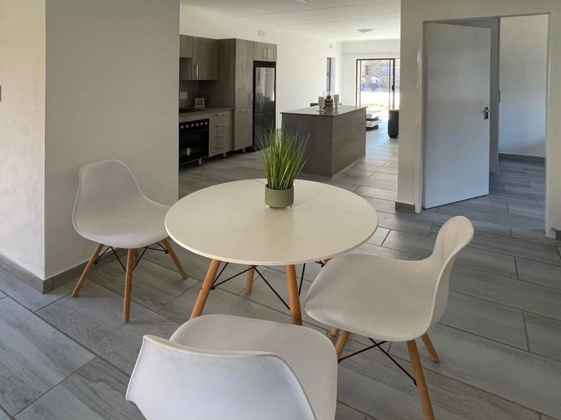 Open plan living area featuring modern tiled flooring, a contemporary kitchen with island, and seamless flow between the dining and kitchen spaces.