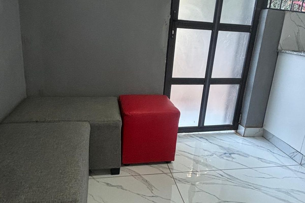 A modern living area featuring high-gloss marble-look floor tiles and a black metal-framed glass door with integrated security bars.
