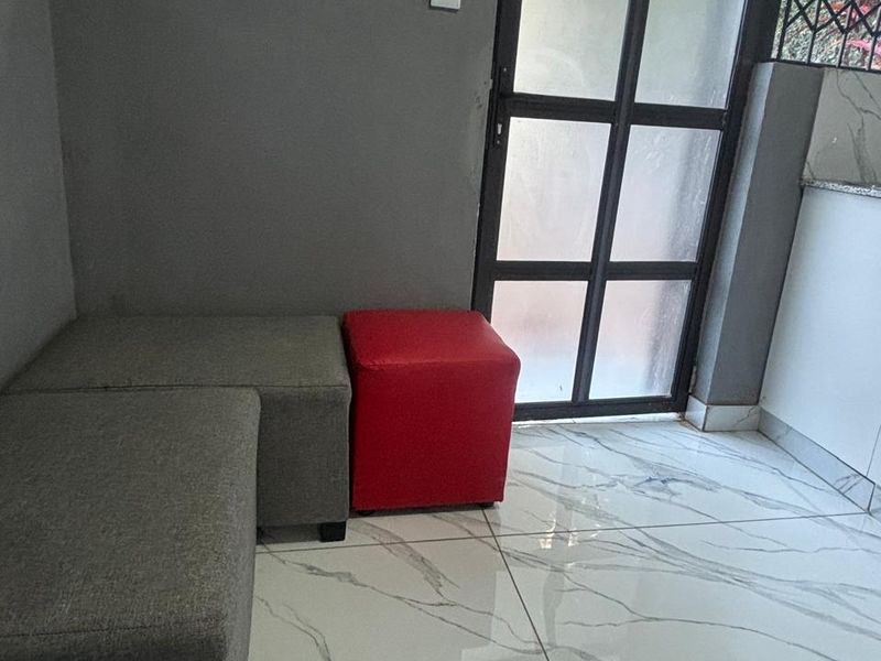A modern living area featuring high-gloss marble-look floor tiles and a black metal-framed glass door with integrated security bars.