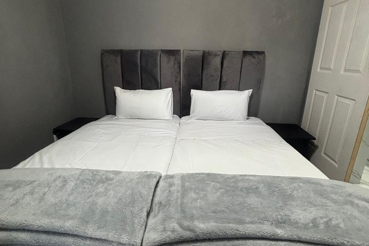 A bedroom featuring a grey accent wall and a visible electrical distribution board panel.