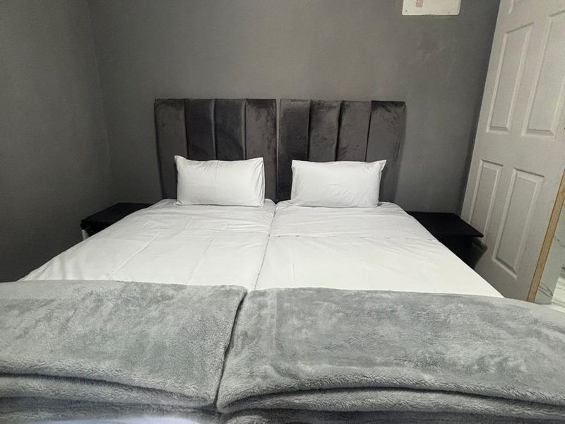 A bedroom featuring a grey accent wall and a visible electrical distribution board panel.