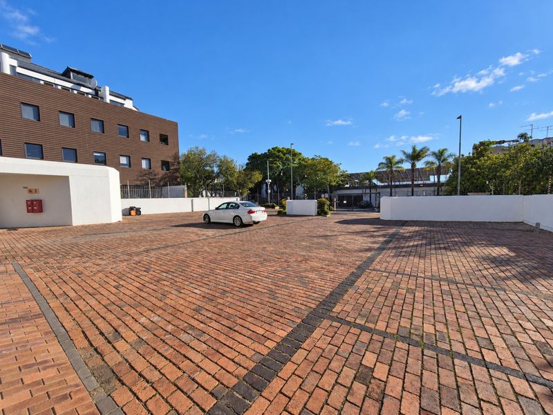 A spacious commercial exterior area featuring a well-maintained brick paved driveway, perimeter walls, and secure fencing.
