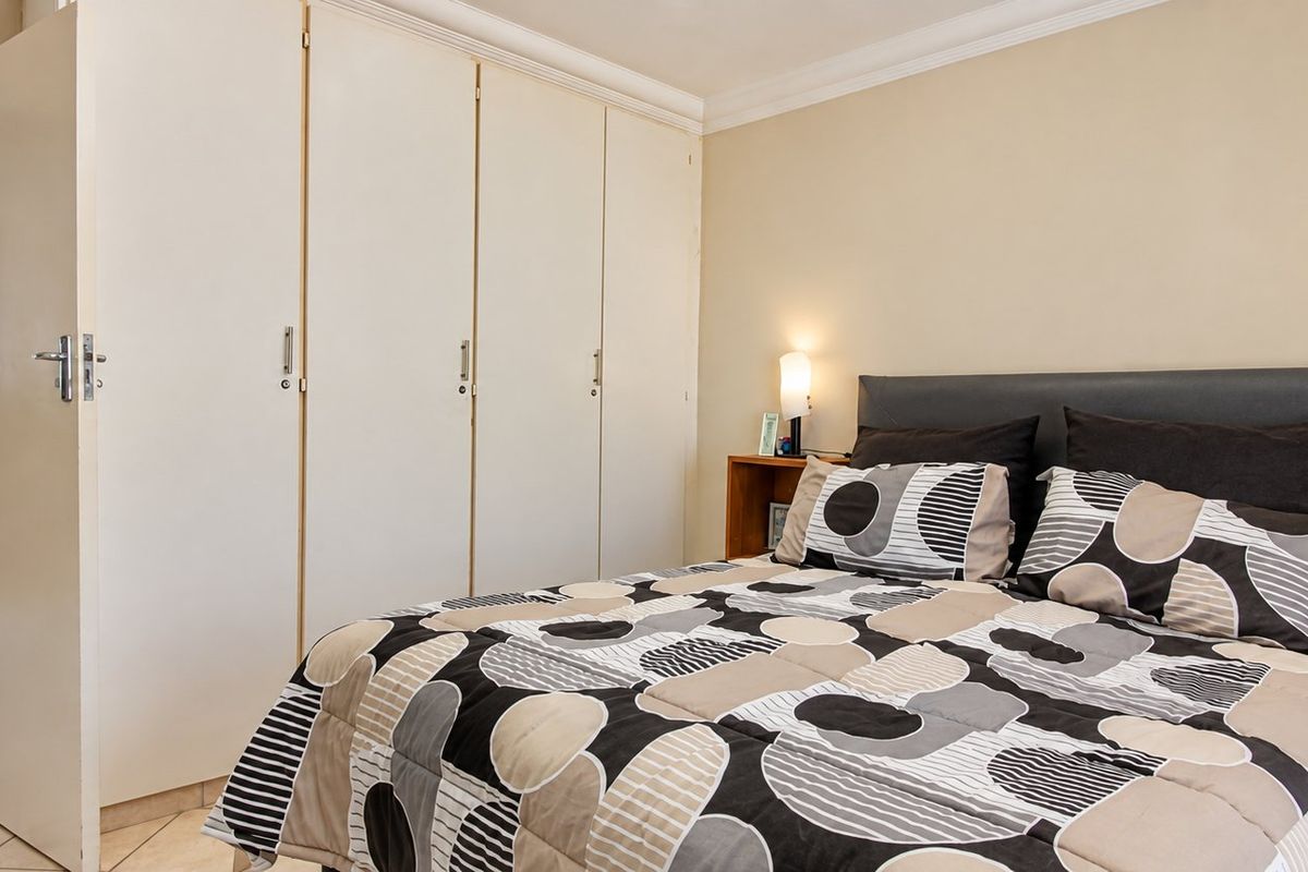 A bedroom featuring built-in cupboards, tiled flooring, and direct access to an en-suite bathroom.