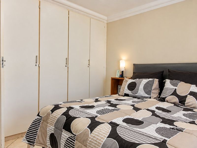 A bedroom featuring built-in cupboards, tiled flooring, and direct access to an en-suite bathroom.