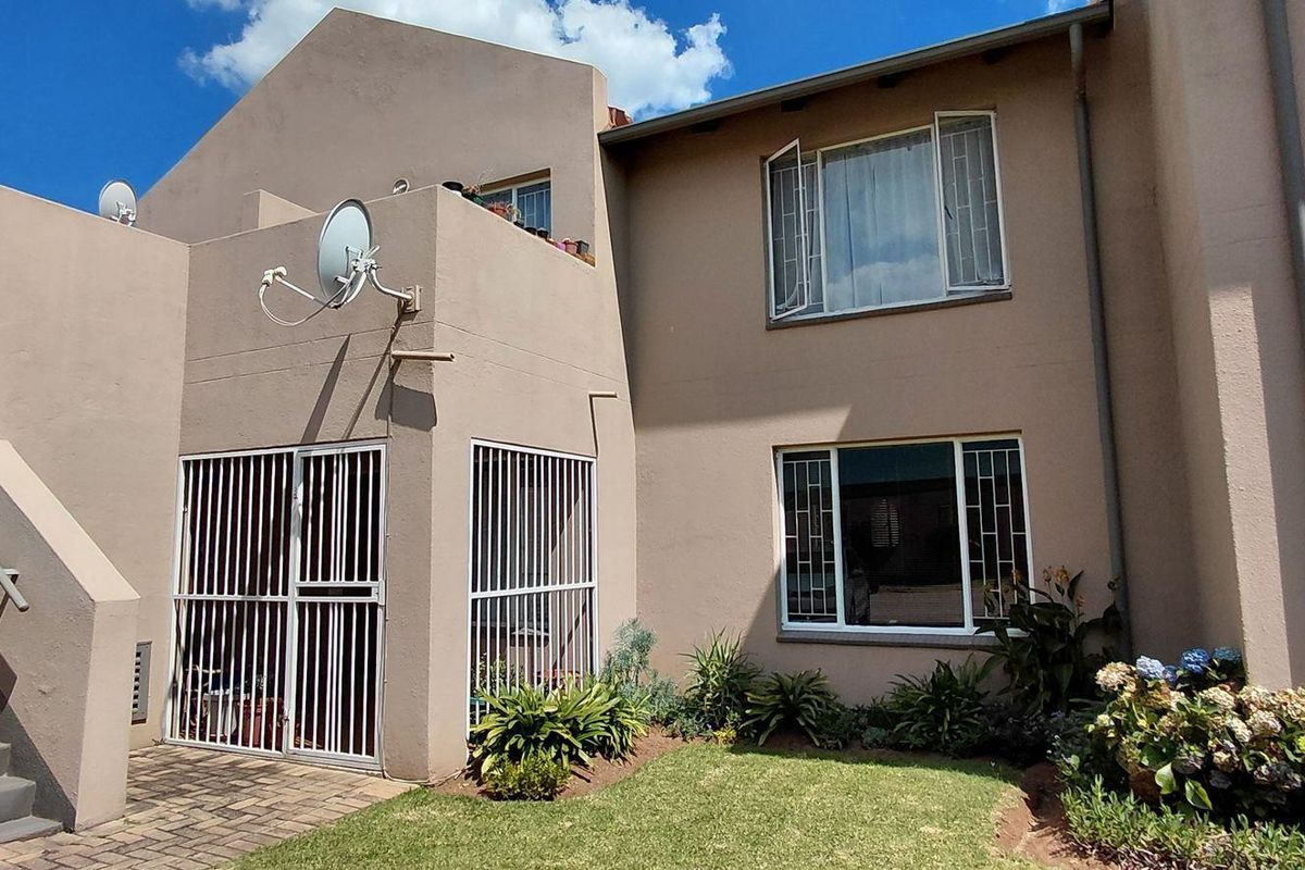 Rear view of the apartment building featuring a paved walkway, external staircase with handrail, and security-fitted windows and doors.