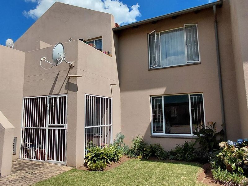 Rear view of the apartment building featuring a paved walkway, external staircase with handrail, and security-fitted windows and doors.