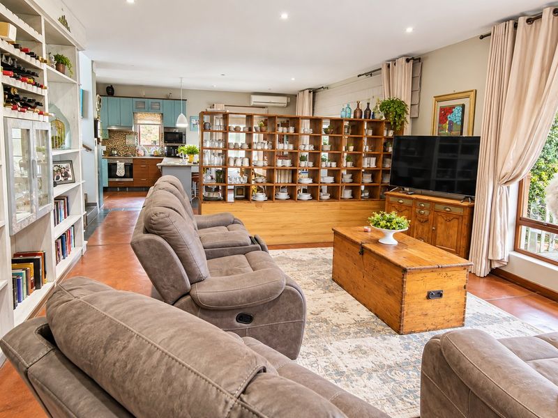 Spacious open-plan living area featuring built-in shelving, a functional kitchen with cabinetry, and integrated appliances, creating a cohesive and well-maintained living space.