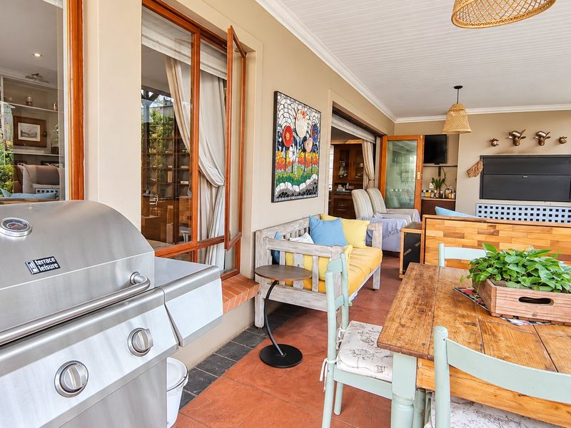 A spacious covered patio featuring tiled flooring, a beadboard ceiling, and a built-in fireplace, perfect for outdoor entertaining and relaxation.