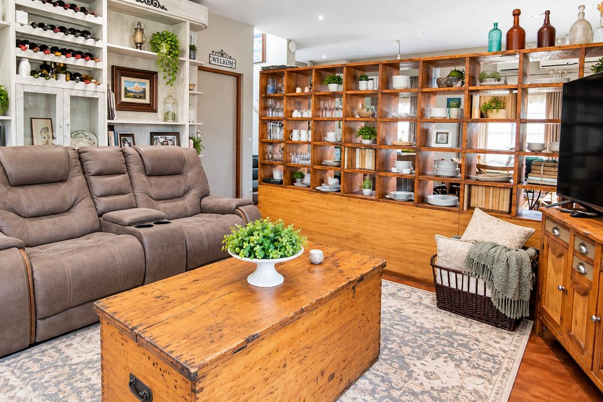 A cozy living room featuring extensive built-in shelving, recessed lighting, and warm-toned laminate flooring, creating a functional and inviting space.